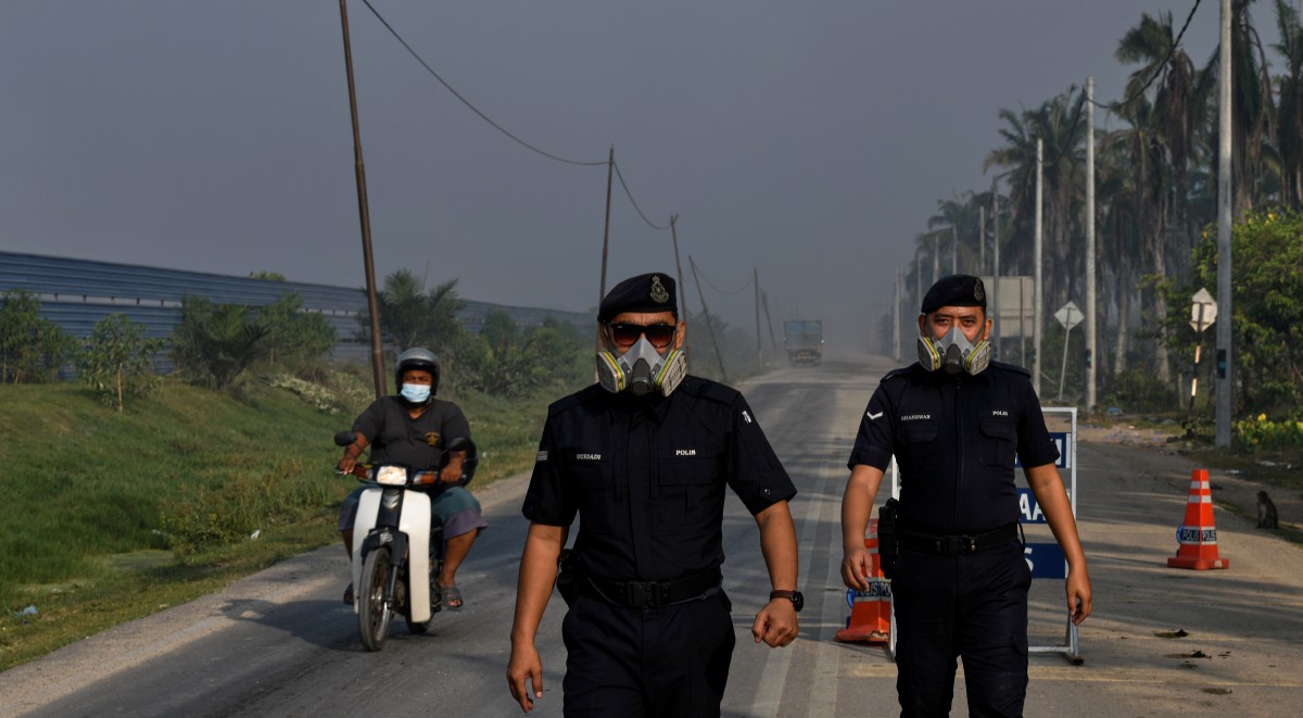 ANGGOTA polis memakai topeng hidung semasa membantu mengawal kawasan tapak pelupusan sampah di Jalan Byram, Pulau Burung. FOTO Bernama