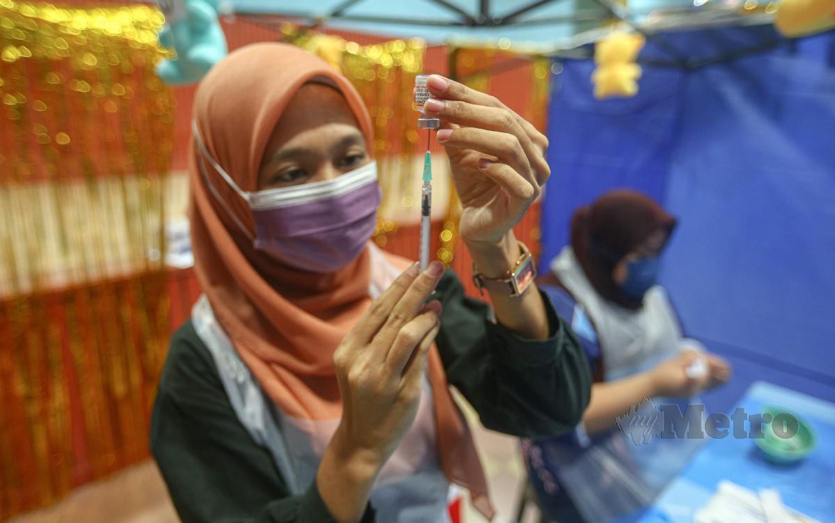 VAKSINATOR sedang menyiapkan picagari yang berisi vaksin kanak-kanak pada Program PICKids di Dewan Datuk Hj Ahmad Ithnin, Merlimau, Melaka. FOTO Syafeeq Ahmad.
