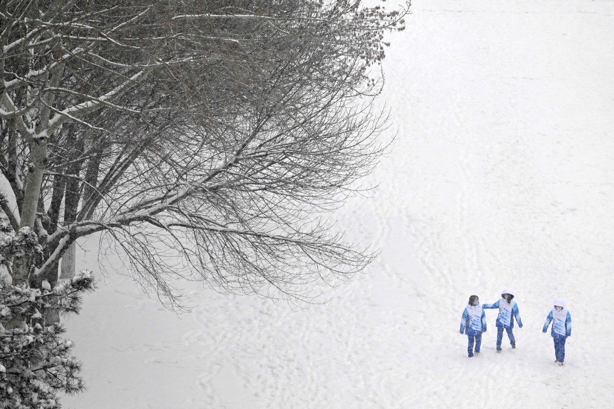 SUKARELAWAN berjalan di dalam salji di luar Pusat Media Utama (MMC) ketika Sukan Olimpik Musim Sejuk di Beijing. FOTO AFP