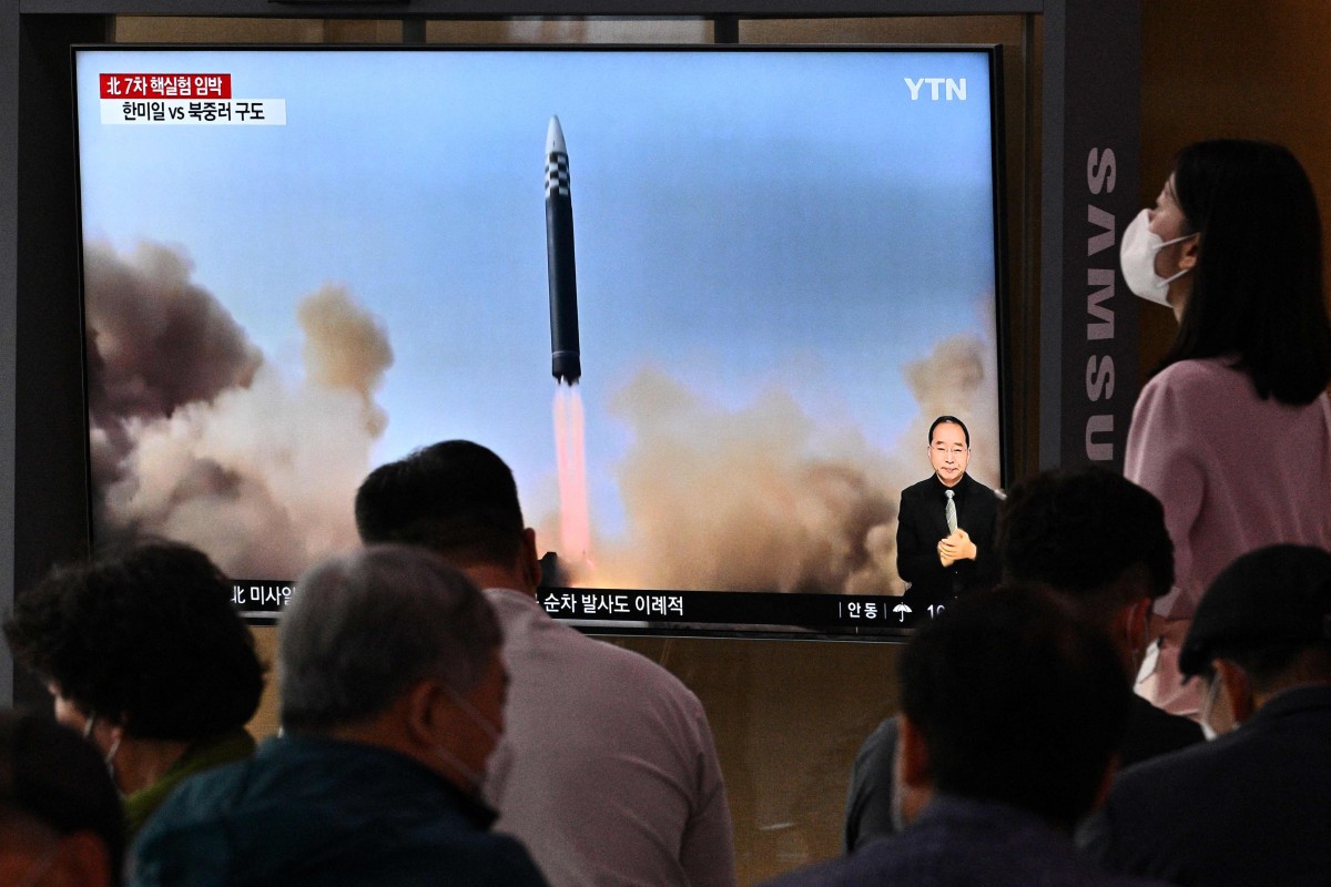 ORANG ramai duduk berhampiran skrin yang menunjukkan siaran berita dengan rakaman fail ujian peluru berpandu Korea Utara. FOTO AFP.