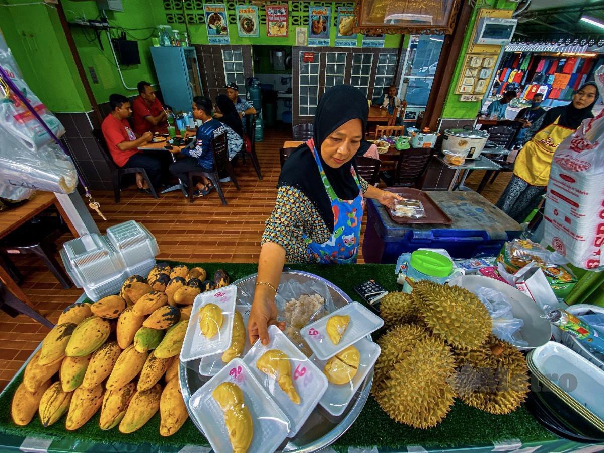 PENIAGA pulut ayam dan mangga, Patimoh Ismail menyiapkan barang untuk menjalankan perniagaan. FOTO Luqman Hakim Zubir