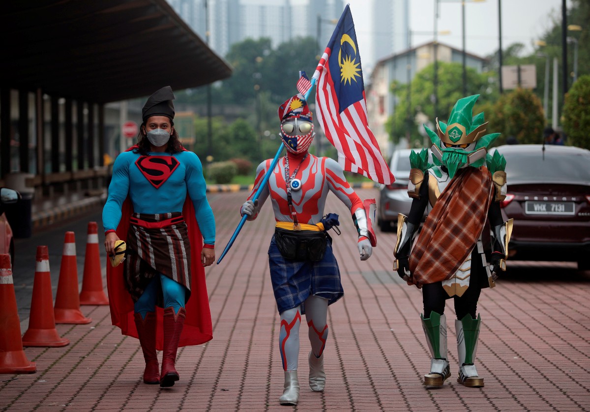(Dari kiri) Mohd Faez; Hafiz dan Farabi Zawali kelihatan bersemangat menggayakan kostum adiwira dan kain pelikat bagi mengikut Program Keretapi Sarong 2022 sempena Hari Malaysia 2022 hari ini. FOTO Bernama.