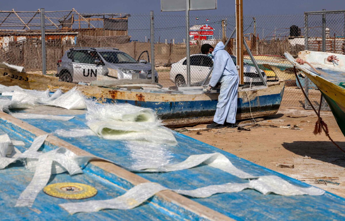 TUKANG menggunakan gentian kaca untuk membaiki bot nelayan. FOTO AFP