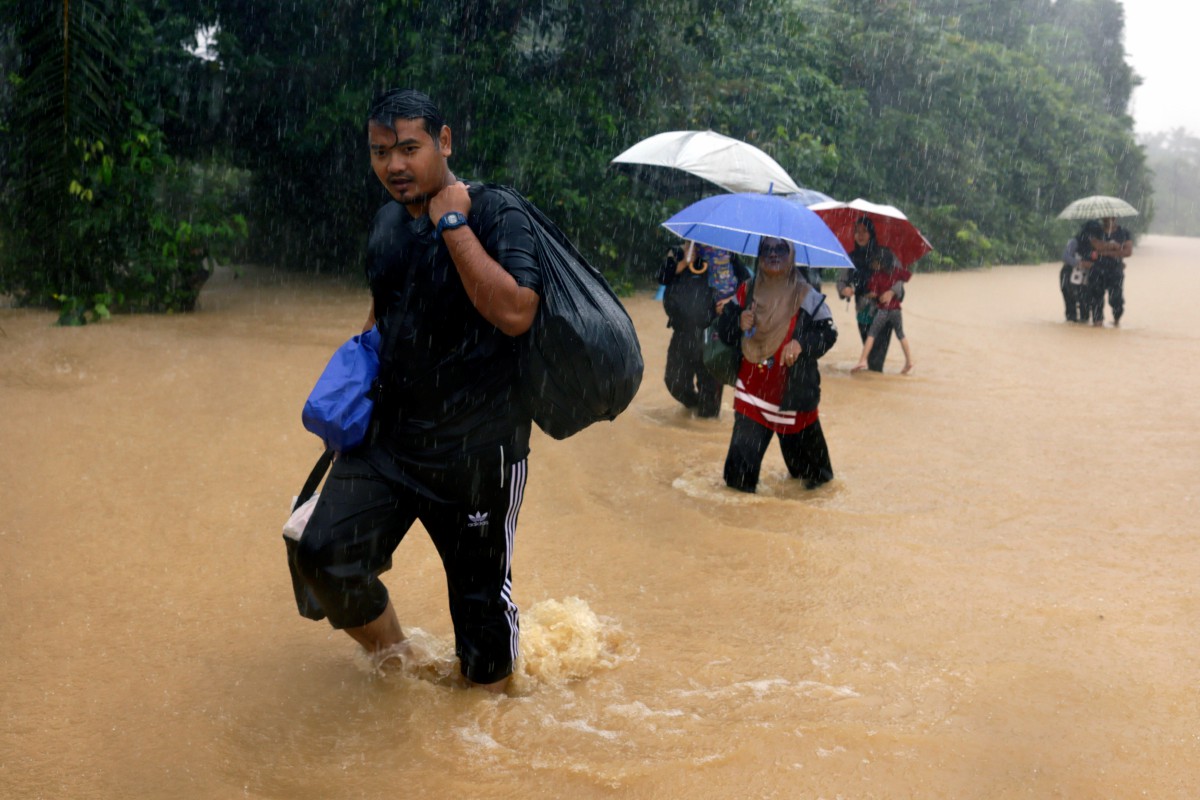 BEBERAPA penduduk mengharungi banjir untuk ke tempat selamat selepas kampung mereka dilanda banjir semasa tinjauan di Kampung Besut hari ini. FOTO Bernama.