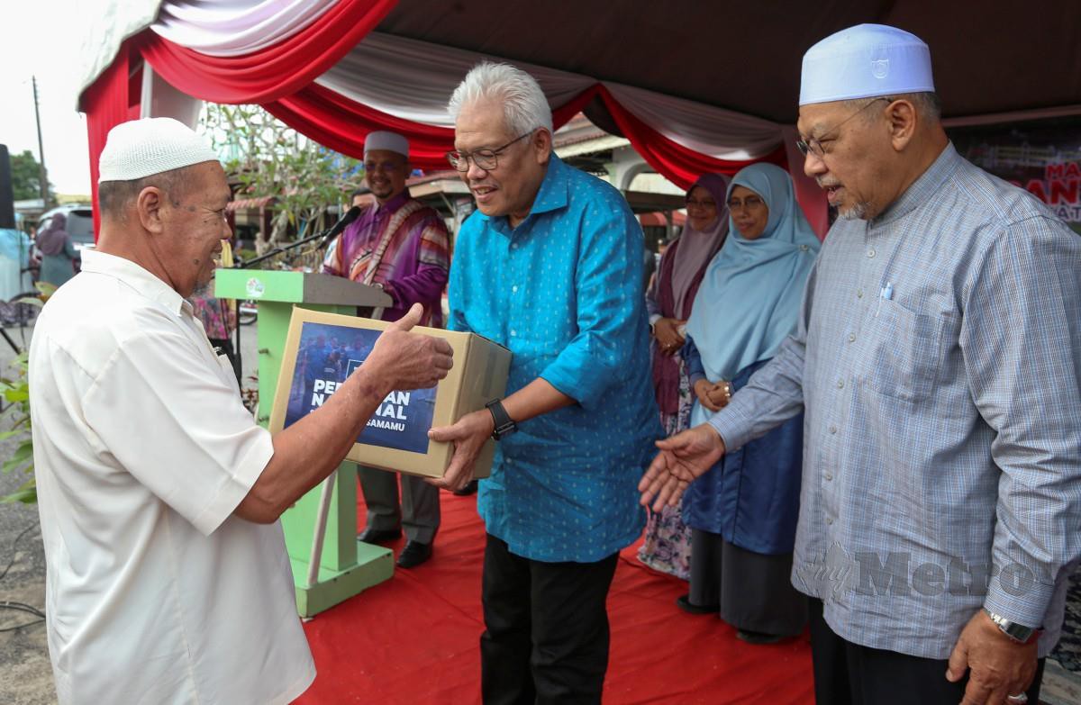 HAMZAH (tengah) diiringi oleh Menteri Besar Kelantan, Datuk Ahmad Yakob (kanan) menyampaikan sumbangan bantuan kepada mangsa banjir. FOTO Nik Abdullah Nik Omar.
