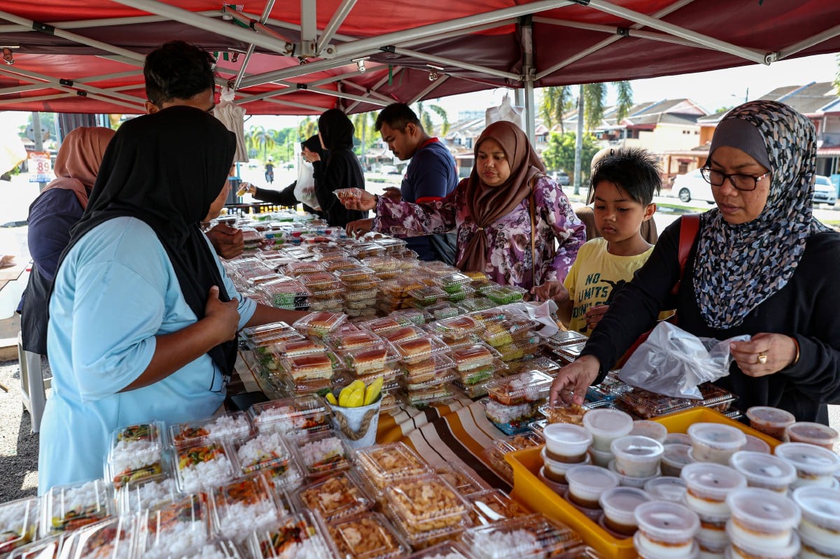 PELANGGAN membeli pelbagai kuih muih yang dijual pada harga RM1 sepaket. FOTO Bernama