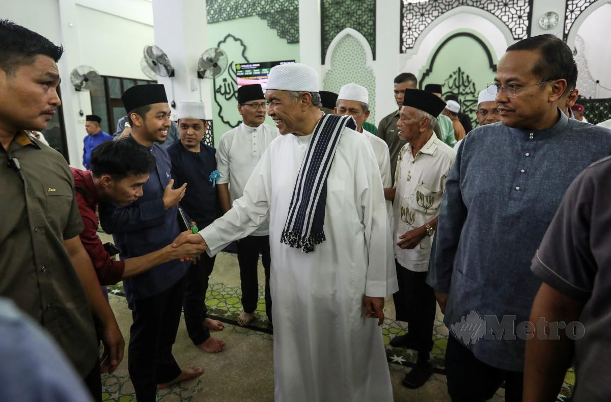 AHMAD Zahid bersalaman dengan jemaah selepas menunaikan solat Maghrib pada majlis Santunan Kasih Ramadan di Masjid Al - Ansar Kem Sri Pantai, Seberang Takir. FOTO Ghazali Kori.