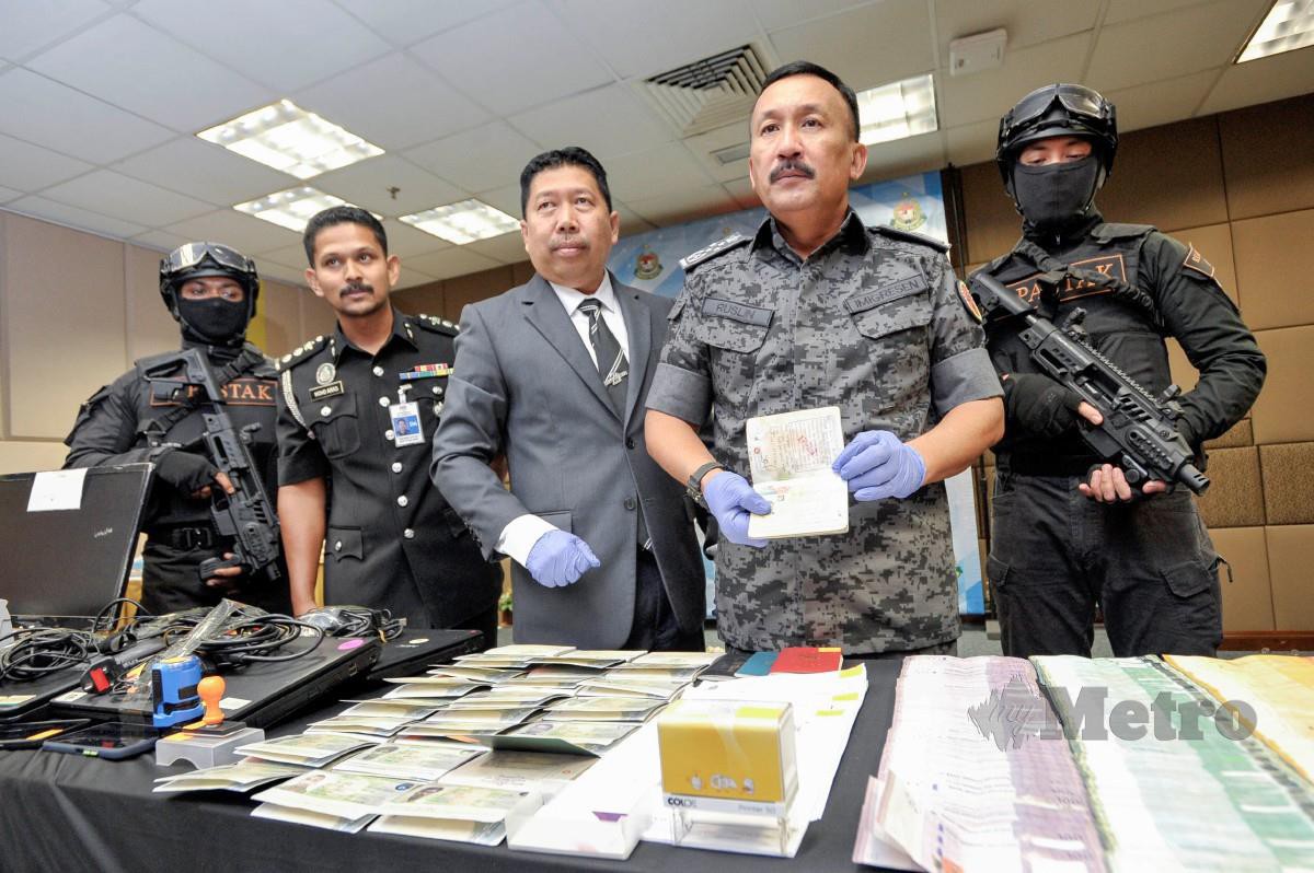 RUSLIN melihat beberapa pasport milik warga asing yang ditahan dalam satu operasi sindiket perjudian membabitkan warga asing ketika sidang media di Jabatan Imigresen Malaysia, Putrajaya. FOTO Aizuddin Saad.