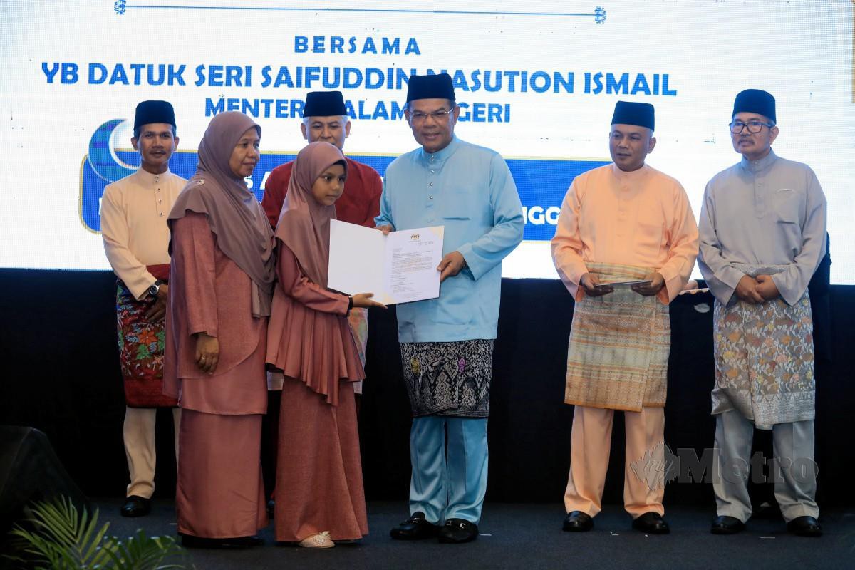 SAIFUDDIN Nasution (tiga kanan) diiringi Ketua Polis Negara Tan Sri Acryl Sany Abdullah Sani (dua kiri) menyerahkan surat keputusan kewarganegaraan kepada penerima terpilih. FOTO Ghazali Kori.