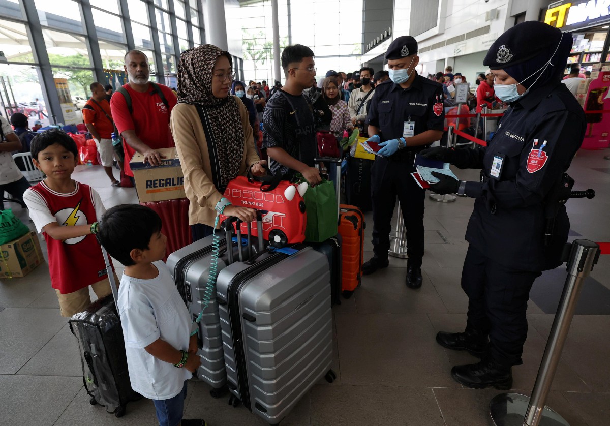 DUA anggota polis bantuan memeriksa pasport dan tiket pelepasan warga Indonesia yang ingin pulang ke kampung halaman sempena Aidilfitri di Terminal Feri Antarabangsa Puteri Harbour. FOTO Bernama.