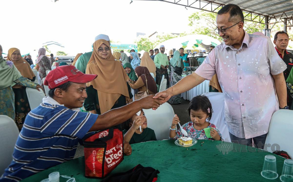 DATUK Seri Dr Ahmad Samsuri Mokhtar (kanan) beramah mesra bersama pengunjung pada majlis Rumah Terbuka Eidulfitri Pas Terengganu di Dataran Shahbandar. FOTO Ghazali Kori.