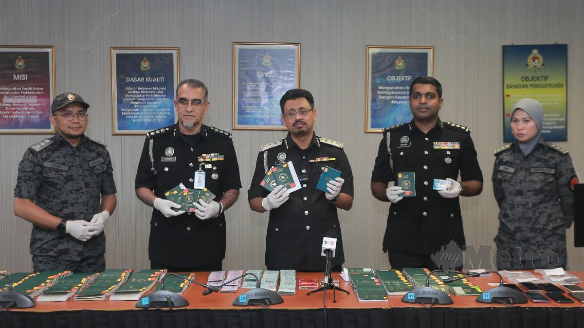  SYAMSUL Badrin (tengah) menunjukkan barang rampasan seperti pasport, wang tunai dan peralatan komputer. FOTO Genes Gulitah.
