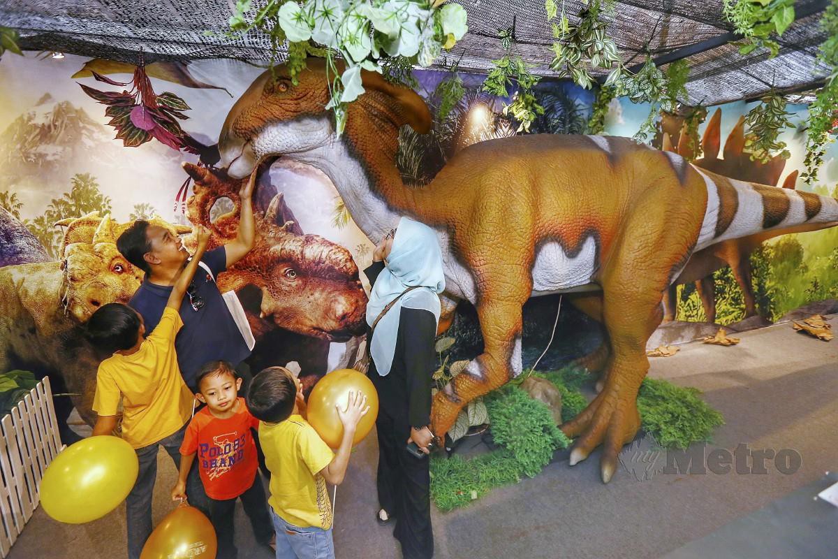 PENGUNJUNG bergambar dengan replika dinosaur di reruai Dino Land sempena Karnival Jom Heboh Selangor Generasi Muda di Dataran Karnival Stadium Shah Alam. FOTO Saifullizan Tamadi.