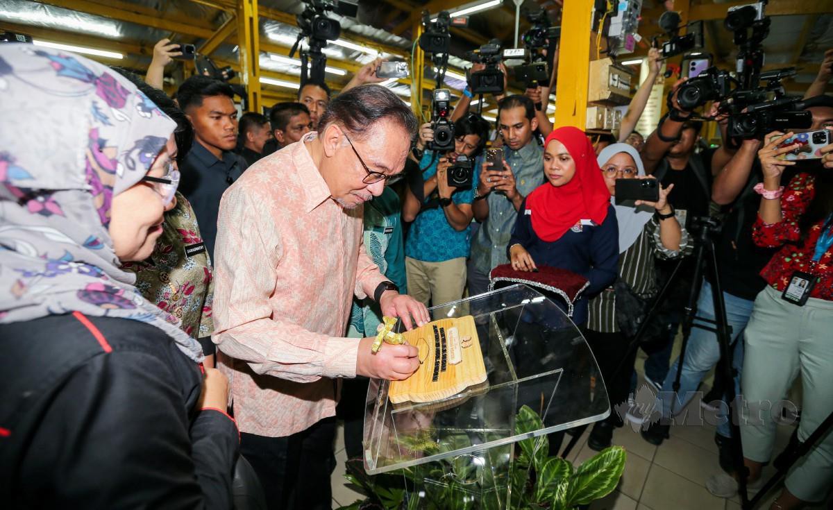 ANWAR menandatangani plat ketika hadir ke Program Temu Mesra Perdana Menteri di Pusat Penjaja Madani, Jalan Tuanku Abdul Rahman, Kuala Lumpur. FOTO Aswadi Alias