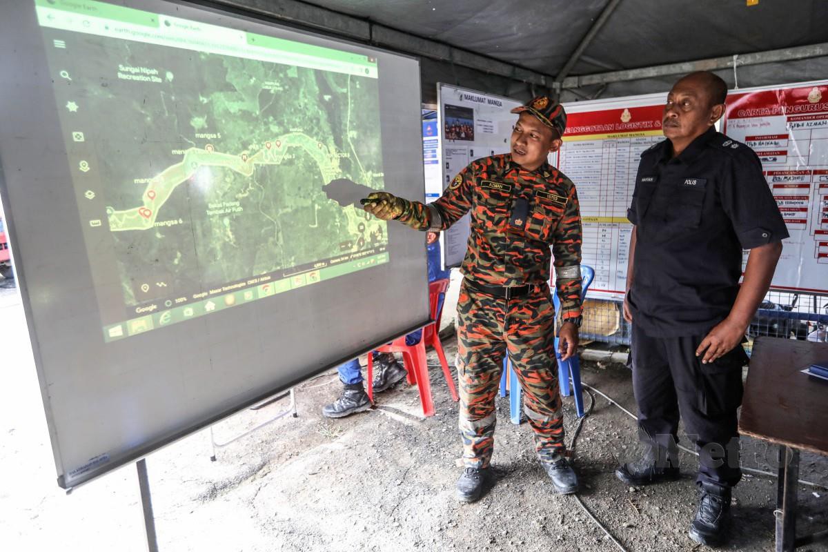 KETUA Polis Daerah Kemaman, Superintendan Hanyan Ramlan (kanan) bersama Azman (kiri) menunjukkan peta lokasi  dalam operasi  tragedi  kepala air di Jeram Air Putih. FOTO Ghazali Kori. 
