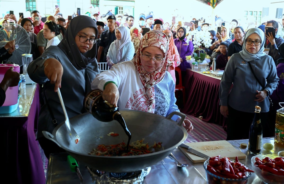 TUNKU Azizah berkenan memasak sambal ikan bilis berlada sewaktu tiba pada program Santapan Rakyat di Dewan Perdana hari ini. FOTO Bernama