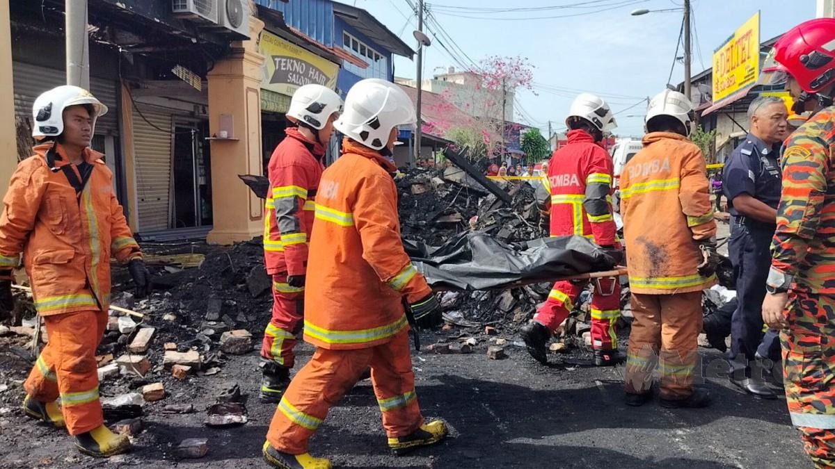 ANGGOTA bomba mengangkat mayat ketiga yang ditemukan rentung dalam kebakaran membabitkan lapan unit rumah kedai di Jalan Sungai Emas, Kota Kuala Muda. FOTO Zuliaty Zulkiffli