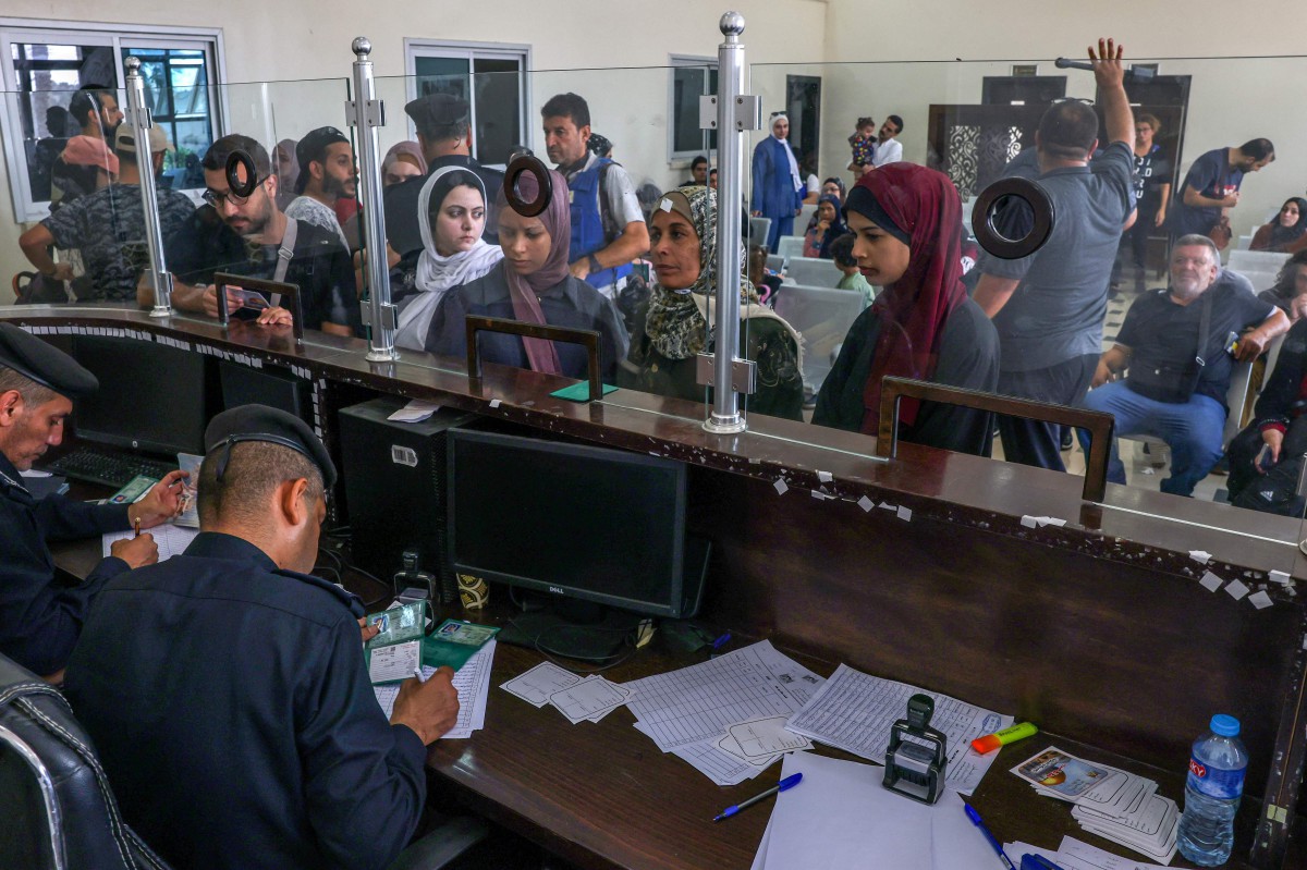 Pengawal sempadan Mesir memeriksa dokumen bagi membolehkan warga asing menyeberangi sempadan Rafah ke Mesir. FOTO AFP
