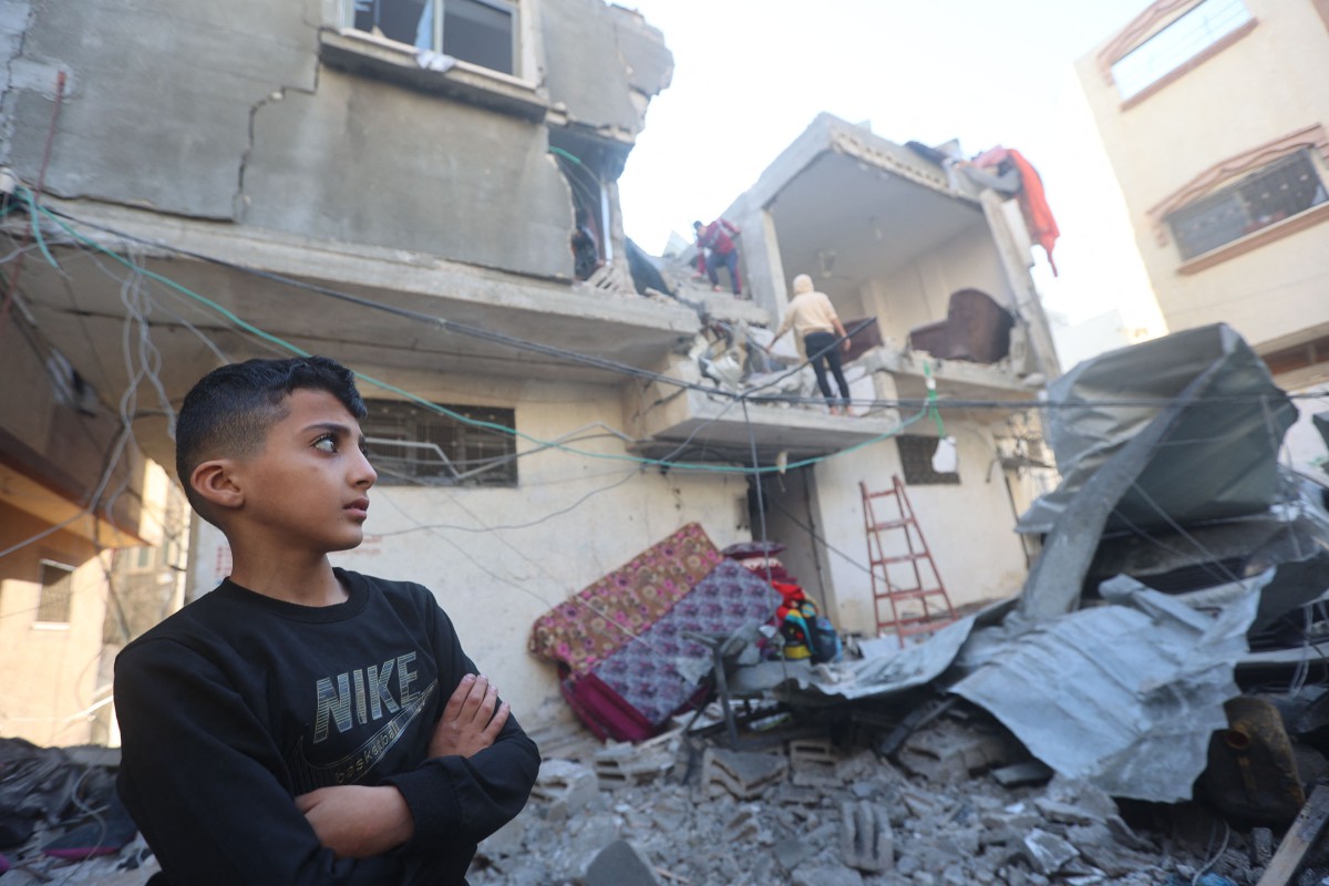 SEORANG kanak-kanak melihat penduduk memeriksa bangunan yang rosak akibat serangan udara Israel. FOTO AFP