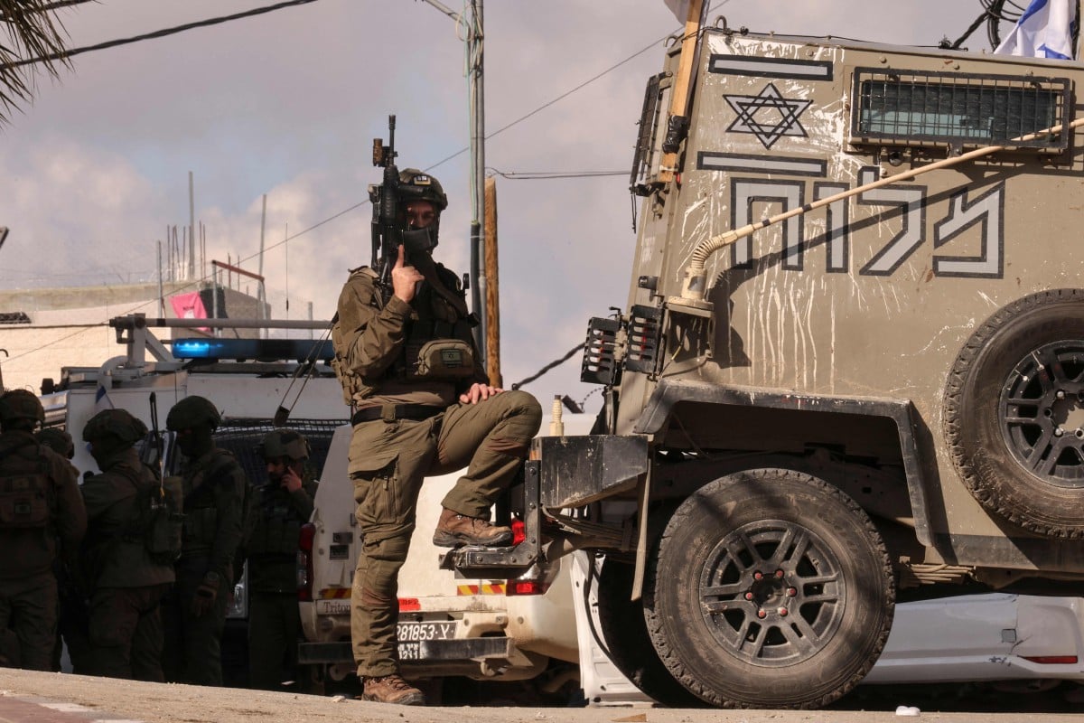 SEORANG tentera Israel membuat kawalan sementara yang lain memeriksa kereta yang dilaporkan digunakan oleh warga Palestin untuk melakukan serangan. FOTO AFP