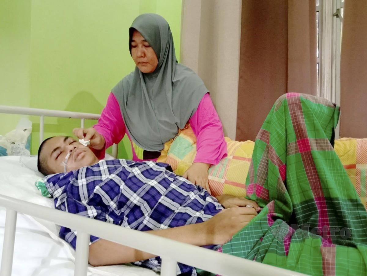 WAN Murni Wan Ngah menguruskan anaknya Muhammad Amirul yang terlantar berikutan saluran darah ke otak pecah. FOTO Nazdy Harun