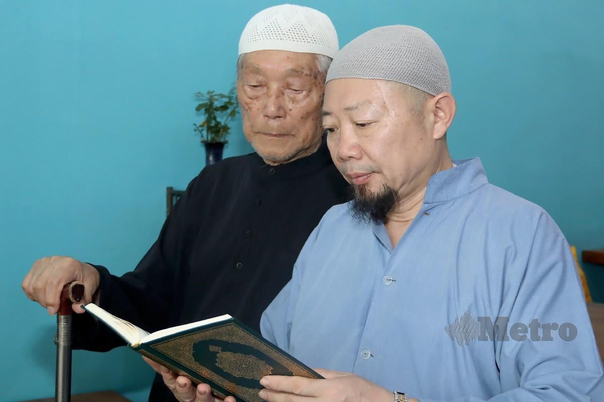 AHMAD Shi Rong Xuan (kanan), membaca al-Quran bersama bapanya, Xing Hua,  (kiri). FOTO Aiman Danial Mohd Hood Aktha