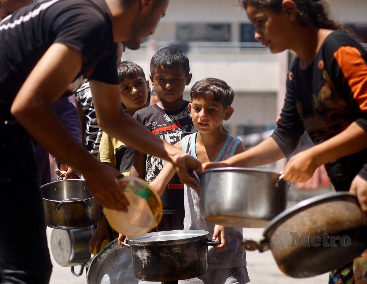 KANAK-kanak Palestin beratur mengambil makanan yang disediakan sukarelawan di Khan Younis. FOTO Reuters
