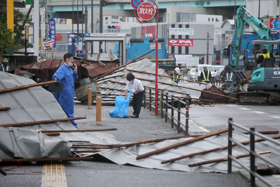 PEKERJA membersihkan atap yang diterbangkan angin kencang akibat Taufan Haishen di Fukuoka. FOTO. AFP 