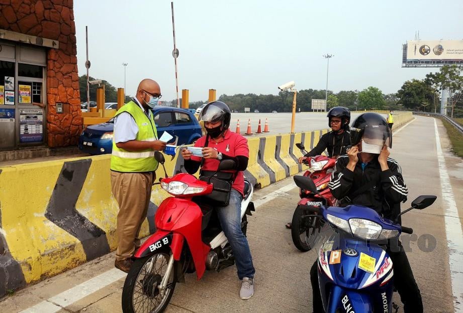 Petugas PROLINTAS mengedarkan topeng muka kepada penunggang motosikal di LKSA berikutan jerebu melanda sekitar Lembah Klang hari ini. Foto Osman Adnan 