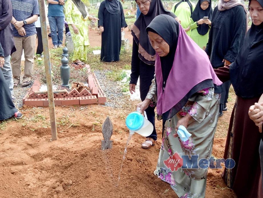 Ibu kepada arwah Nizam,  Mun Ahmad menyiram air di Tanah Wakaf Perkuburan Islam Raudatul Mukminin di Kampung Alai. FOTO Ahmad Ismail