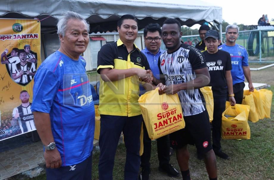 Pengarah Urusan GLE Centre Enterprise, Mohd Zulkifli Harun (dua kiri) bersama Jurulatih Terengganu FC (TFC), Irfan Bakti Abu Salim (kiri) menyampaikan kopi kepada Tchetche Kipre di Padang Kompleks Sukan Gong Badak. 