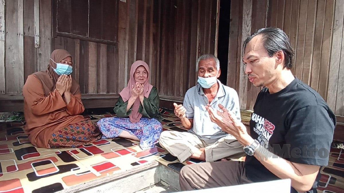 DR Ahmad Azrin (kanan) berdoa bersama keluarga Wan Noriah selepas menghulurkan bantuan pada Program KAHA 2022 di Kampung Merbau Patah. FOTO ZAID SALIM