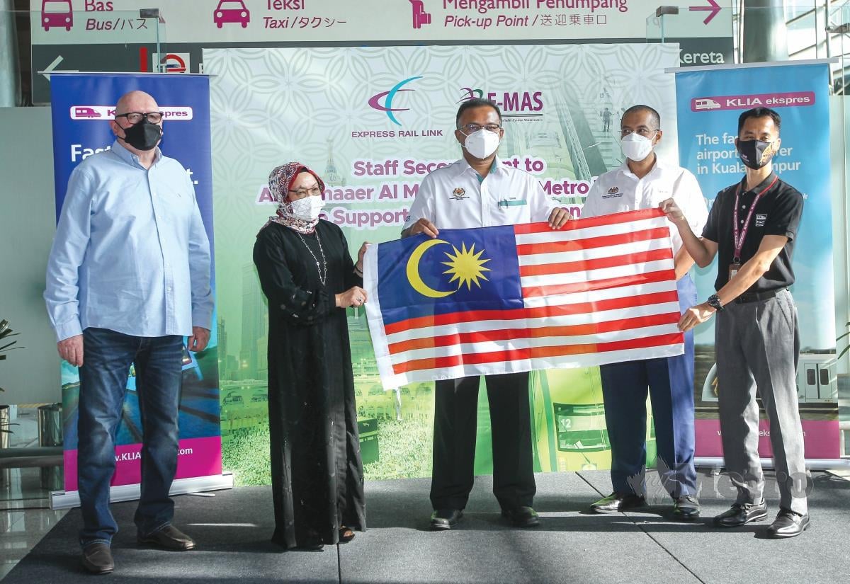 KETUA Setiausaha Kementerian Pengangkutan Malaysia, Datuk Isham Ishak (tengah) menyerahkan Jalur Gemilang kepada Putera Wan Jaffri mewakili kakitangan ERL yang bertugas pada musim haji tahun ini.