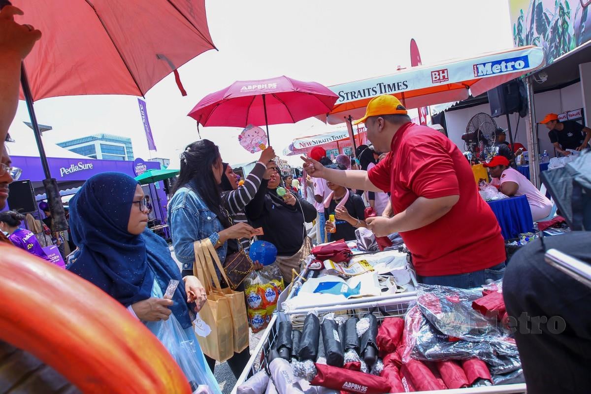 PENGUNJUNG mendapatkan payung di reruai NSTP ketika Karnival Jom Heboh Edisi Raya, Putrajaya. FOTO Aziah Azmee