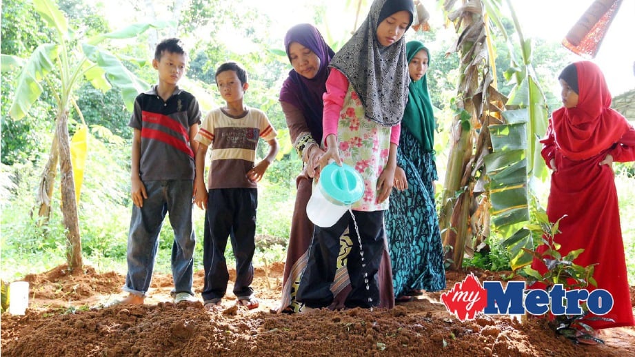 ANAK arwah, Siti Nor Zullaikha Mohd Zaini, 12, menyiram air ke pusara ayah disaksi adik-adiknya, Mohd Faizal Mohd Zaini, 10, (kiri) dan Mohd Fakrullah Mohd Zaini, 8, (dua kiri) serta ahli keluarga. FOTO Faris Zainuldin