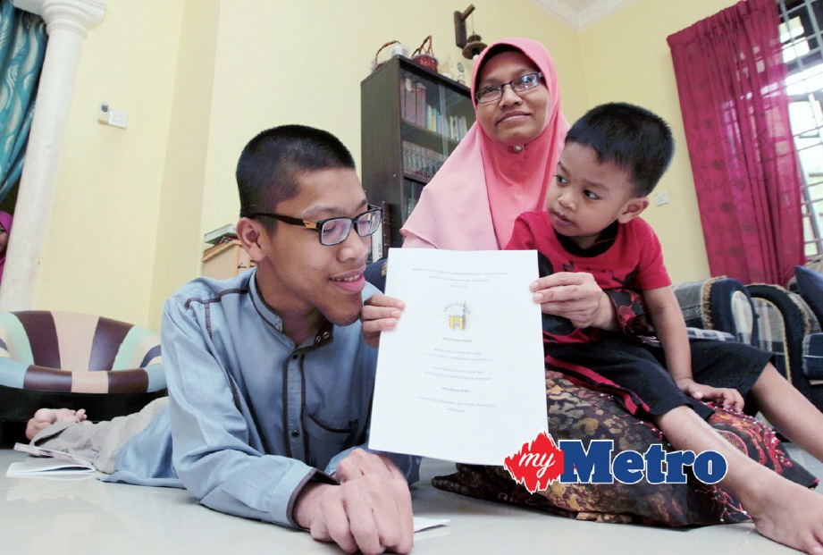 AHMAD Faiz bersama ibunya, Zalina Mohd Kasim, 42, menunjukkan syarat permohonan ke IUM. FOTO Syamsi Suhaimi
