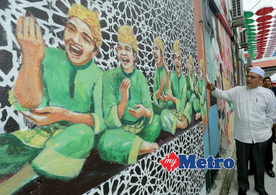 AHMAD Yakob tertarik melihat lukisan dinding di lorong seni di kawasan bebas cukai Pengkalan Kubor. FOTO Fathil Asri