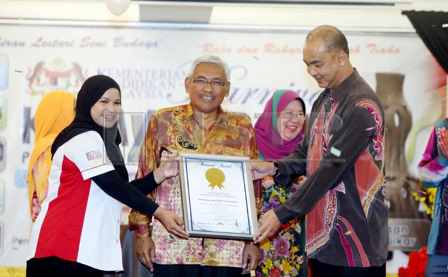 DR Abdul Aziz (tengah) menyaksikan Siti Hajar (kiri) menyerahkan sijil MBR kepada Aznan selepas kejayaan 76 pelajar pendidikan khas menghasilkan kek sepanjang 50.2 meter. FOTO Muhaizan Yahya. 