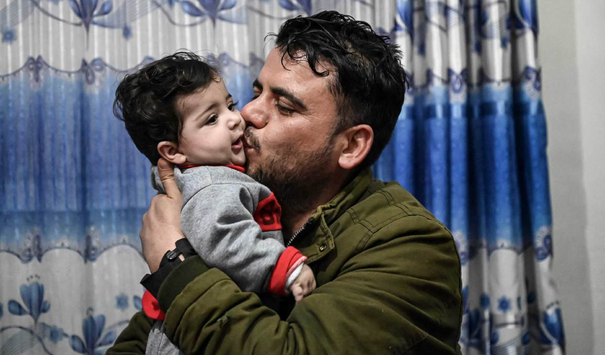 HAMID Safi (kanan) mencium Sohail Ahmadi yang terpisah daripada ibu bapanya di lapangan terbang ketika kekecohan pengunduran tentera AS dari Afghanistan pada 19 Ogos tahun lalu. FOTO AFP
