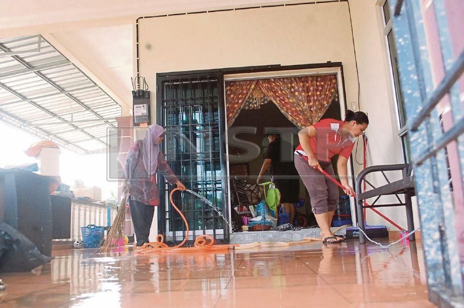 PENDUDUK membersihkan rumah yang ditenggelami air dalam kejadian banjir di Kampung Ganun, Gadek, Alor Gajah, hari ini. Foto HASSAN OMAR