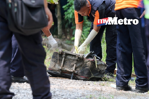 Anggota polis memeriksa beg berisi mayat yang dijumpai di tepi parit di Jalan Belimbing, Meru, semalam. - Foto Fail