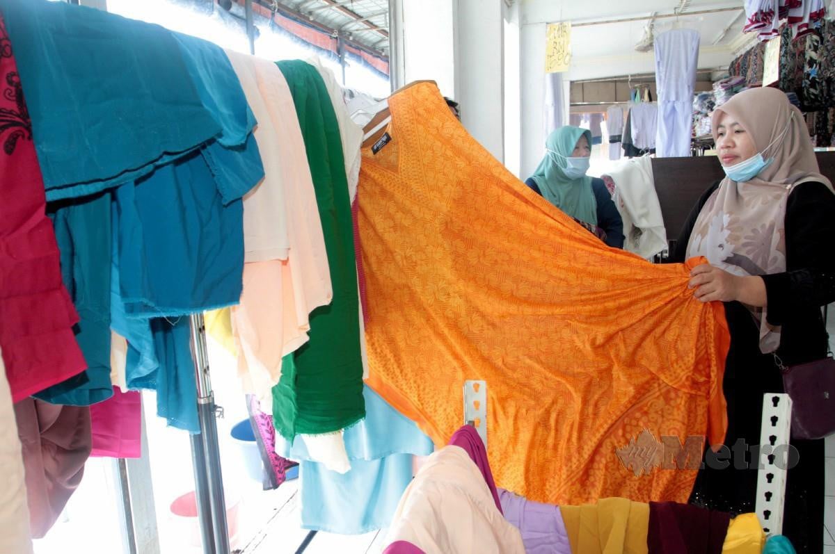 PENIAGA kedai baju dan kain di Kota Tinggi, Fauziah Salleh menyidai baju yang dicuci selepas tenggelam dalam banjir. FOTO Zain Ahmed.