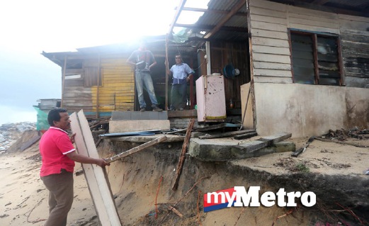 ABDULLAH Mat Isa, 52, (Kiri) melihat bahagian belakang rumahnya yang musnah dipukul ombak besar di Kampung Tanjung Gelam. FOTO Aswadi Alias