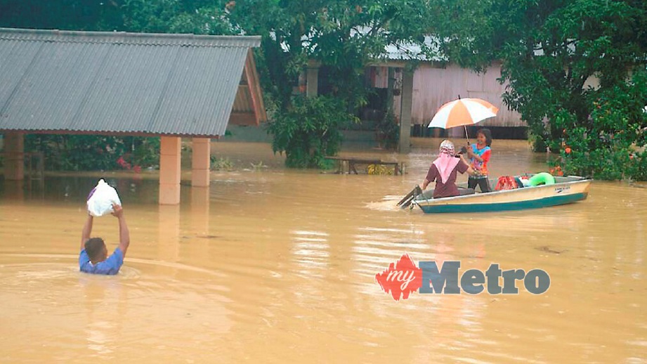 PENDUDUK meredah banjir untuk pulang ke rumahnya di Kampung Nyatoh, Setiu. FOTO Nurul Fatihah Sulaini