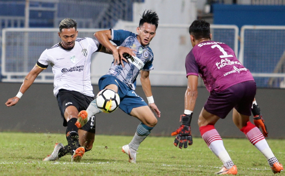 PEMAIN Terengganu FC II, Bruno Junichi Suzuki Castanheira (kiri) diasak oleh pemain Sarawak ketika melakukan sepakan di gawang gol lawan dalam aksi kumpulan A Piala Cabaran 2018 di Stadium Sultan Ismail Nasiruddin Shah. FOTO Rozainah Zakaria