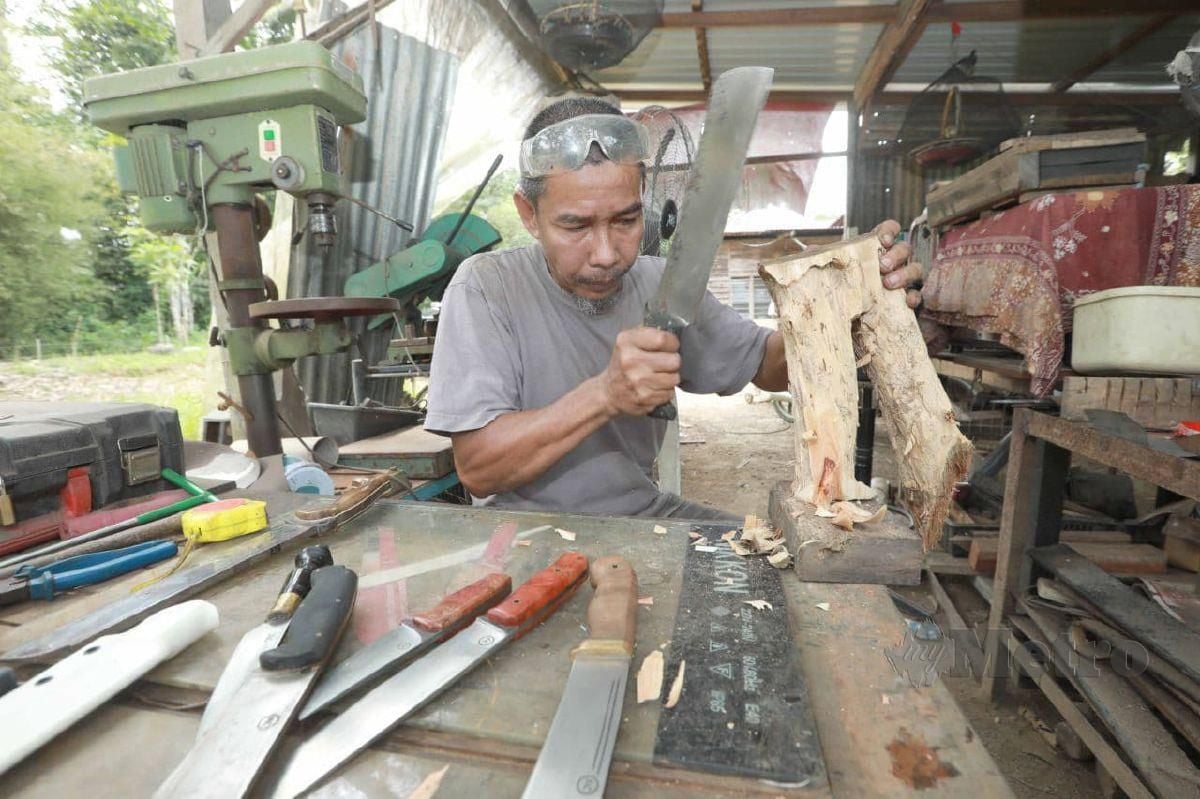 KAMARUZAMAN mencuba parang yand dihasilkan dibengkelnya di Kampung Tersang. FOTO MOHD RAFI MAMAT