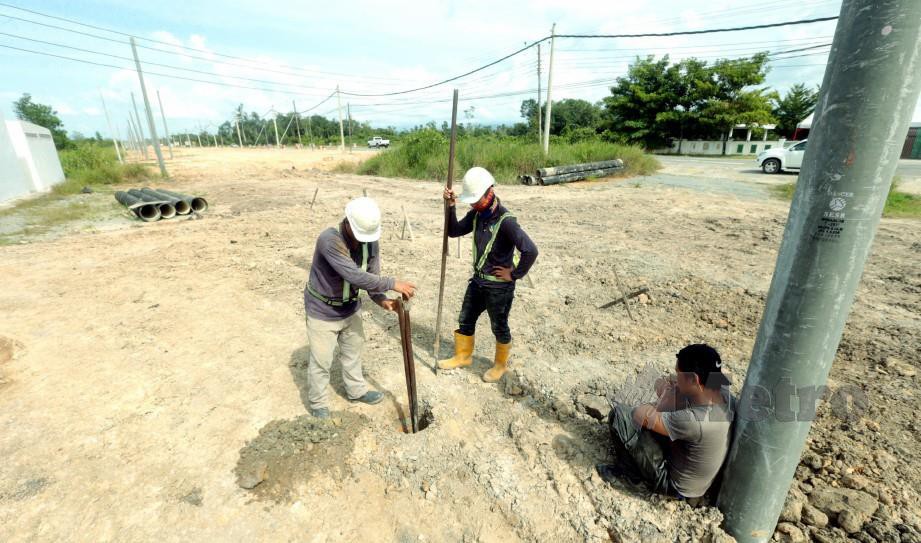 PEKERJA kontraktor memindahkan tiang elektrik bagi memberi laluan kerja penimbusan tanah untuk melebarkan jalan sedia ada yang terbabit dalam projek Lebuhraya Pan Borneo Sabah di kawasan Kimanis. FOTO Edmund Samunting