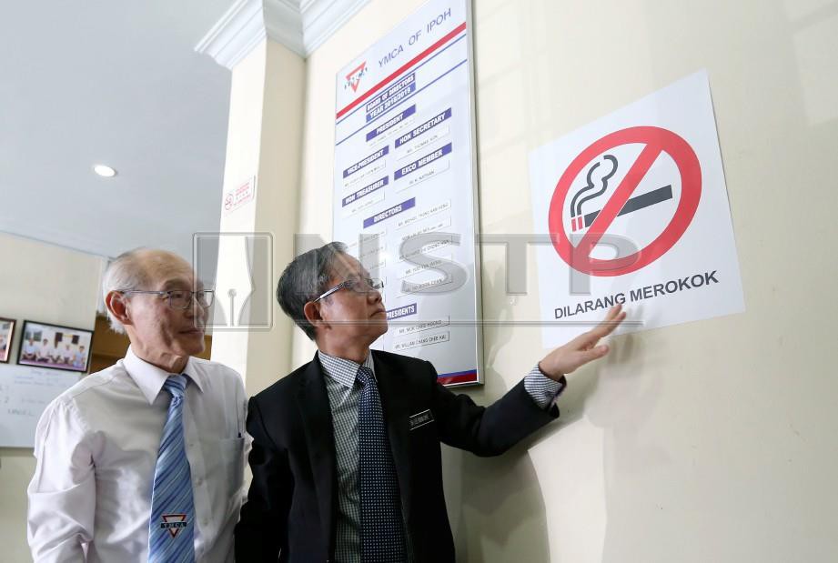 Dr Lee (kanan) menampal poster larangan merokok selepas merasmikan pengisytiharan YMCA Ipoh sebagai kawasan larangan merokok. FOTO Effendy Rashid