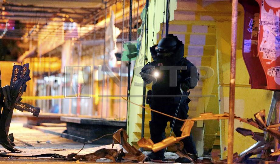 ANGGOTA Unit Pemusnah Bom PDRM lengkap berpakaian khas kalis bom memeriksa lokasi kejadian letupan yang berlaku di kedai emas di Segama, Kota Kinabalu. FOTO Malai Rosmah Tuah