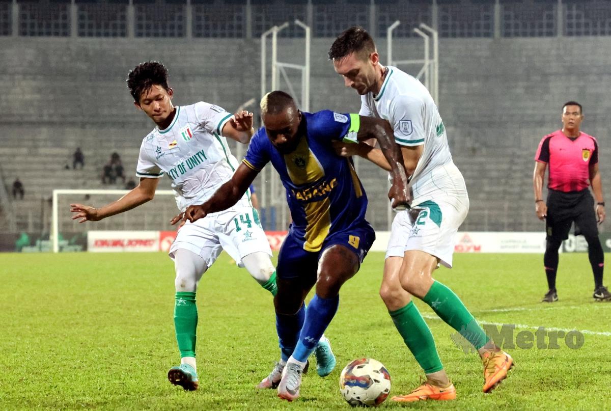 PENYERANG import Sri Pahang FC, Kpah Sherman (tengah) diapit dua pemain Kuching City FC pada perlawanan malam tadi. FOTO BERNAMA 
